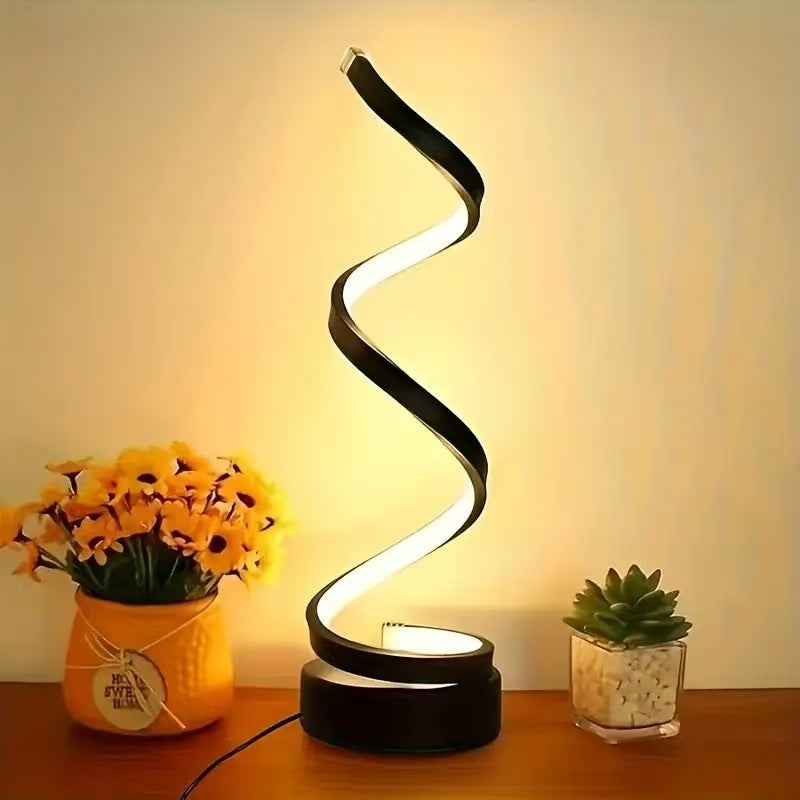 Spiral LED lamp on a wooden surface with decorative plants